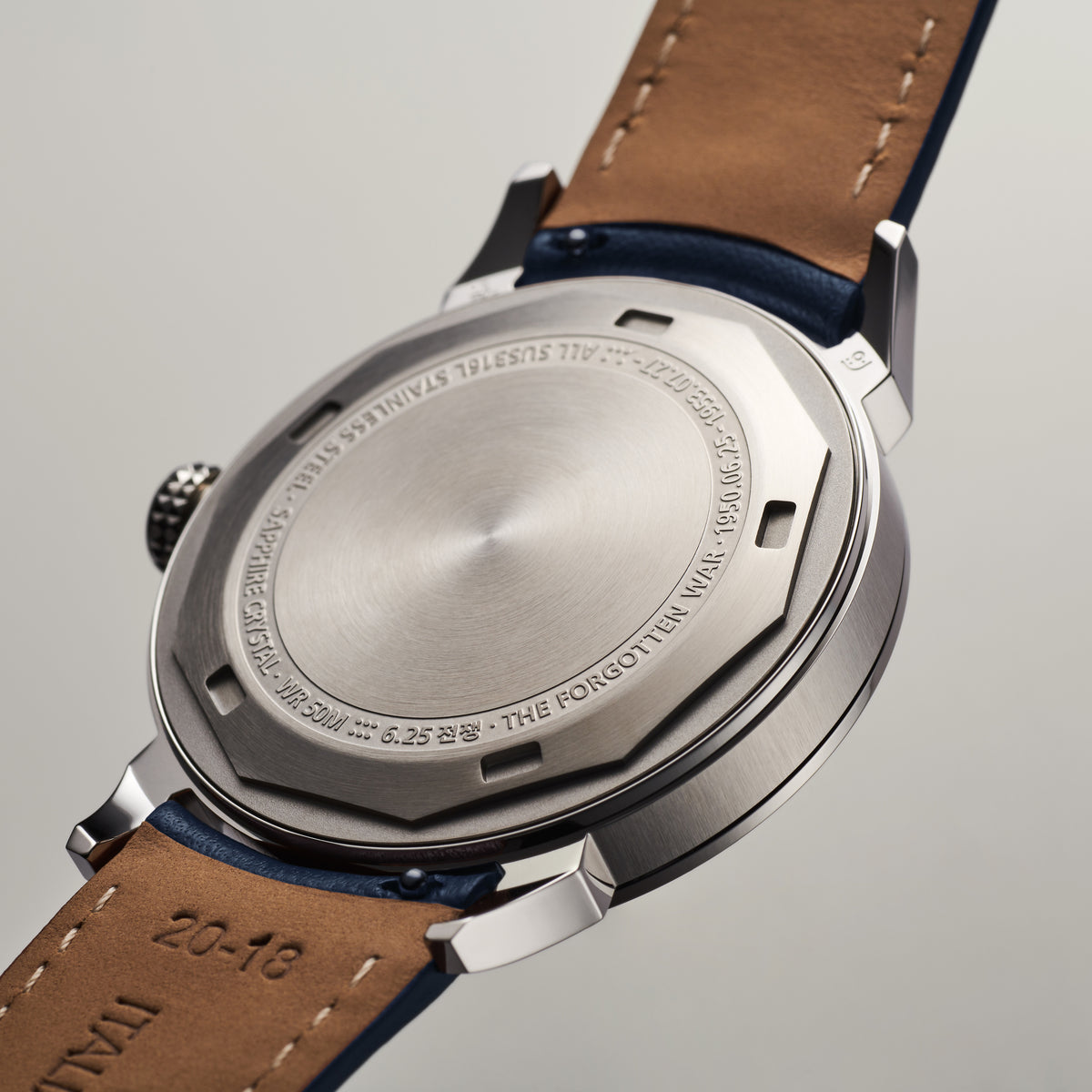 GYRE-0001 Dust stainless-steel case back with engraved markings, navy leather strap showing tan underside