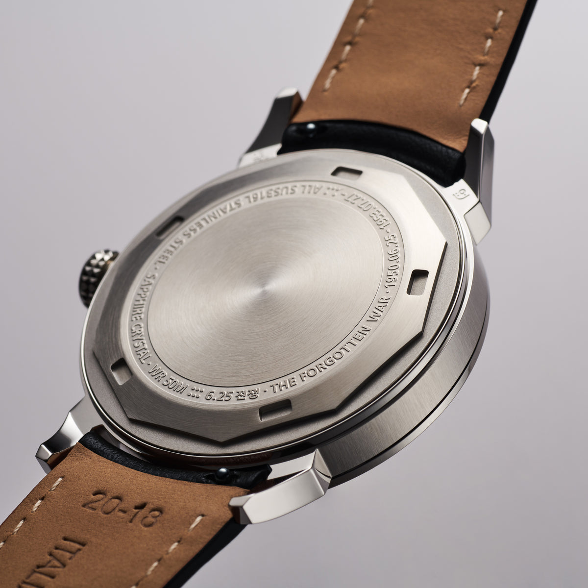 GYRE-0001 Smoke stainless-steel case back with engraved markings, black leather strap showing tan underside